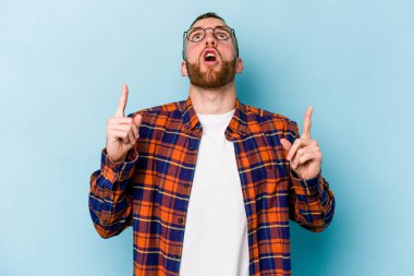Mavi arka planda izole edilmiş beyaz bir adam ağzı açık bir şekilde üst tarafı işaret ediyor..