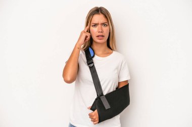 Young caucasian woman with broken hand isolated on white background showing a disappointment gesture with forefinger.