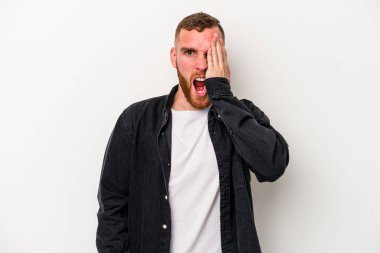 Beyaz arka planda izole edilmiş genç beyaz bir adam yüzünün yarısını palmiye ile örterek eğleniyor..