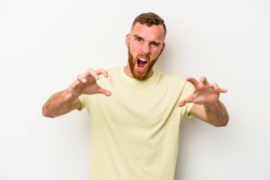 Beyaz arka planda izole edilmiş genç beyaz bir adam pençelerini kedi taklidi yaparken gösteriyor, agresif bir hareket..