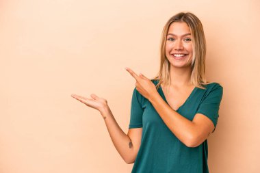 Beyaz tenli genç bir kadın, bej arka planda izole edilmiş. Elinde bir fotokopi odası olduğu için heyecanlı..