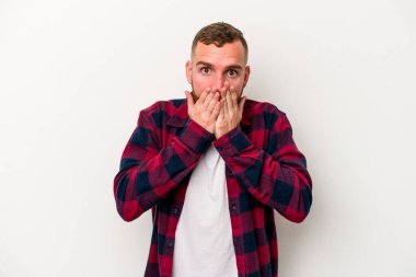 Beyaz arka planda izole edilmiş genç beyaz adam şok olmuş, ağzı ellerle kaplanmış, yeni bir şey keşfetmeye hevesli..