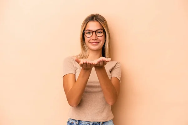 Joven Mujer Caucásica Aislada Sobre Fondo Beige Sosteniendo Algo Con —  Fotos de Stock