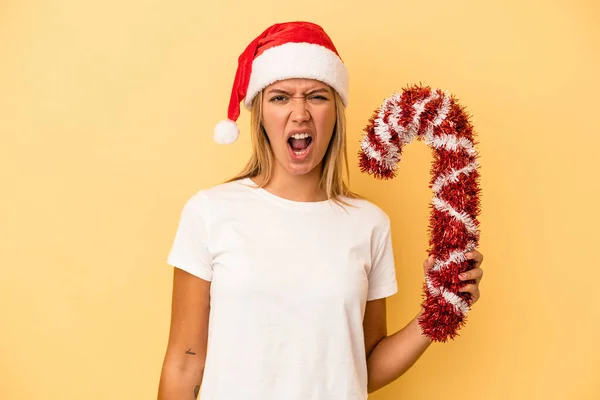 若いですCaucasian女性保持大クリスマススティック隔離上の黄色の背景悲鳴非常に怒っていると積極 — ストック写真