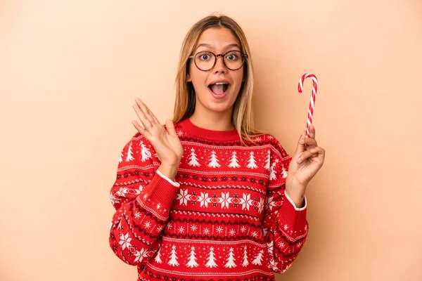 Young Caucasian Woman Holding Christmas Stick Isolated Beige Background Surprised — Stok fotoğraf