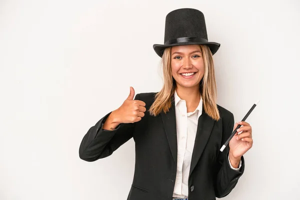 Young caucasian wizard woman holding wand isolated on white background smiling and raising thumb up
