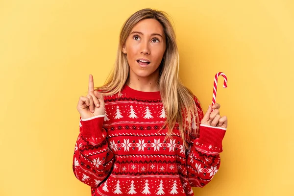 Mladá Běloška Žena Drží Vánoční Hůl Izolované Žlutém Pozadí Ukazuje — Stock fotografie