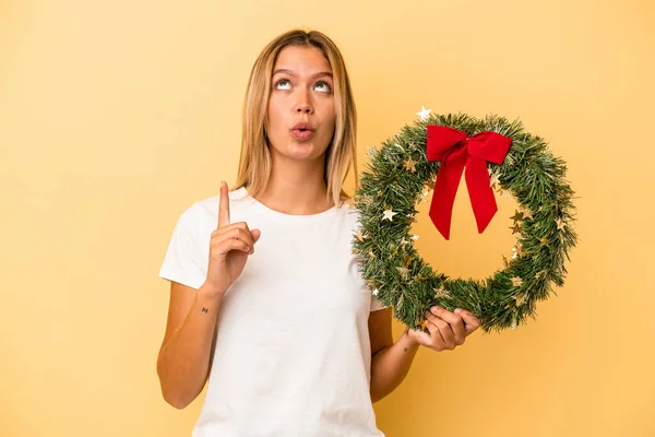 Ung Kaukasisk Kvinna Som Håller Julkrans Isolerad Gul Bakgrund Pekar — Stockfoto