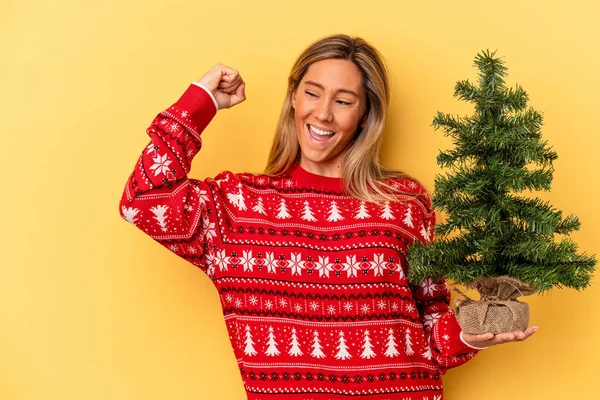 Mladá Běloška Drží Malý Vánoční Stromek Izolované Žlutém Pozadí Zvedající — Stock fotografie