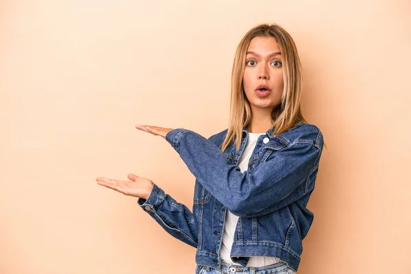 Mujer Caucásica Joven Aislada Sobre Fondo Beige Sorprendida Sorprendida Sosteniendo — Foto de Stock