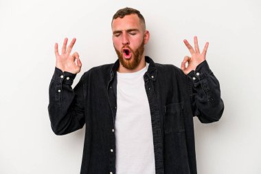 Beyaz arka planda izole edilmiş genç beyaz adam yoğun bir günün ardından rahatlıyor. Yoga yapıyor..