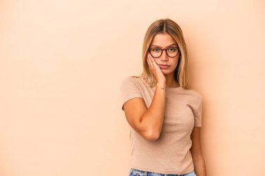 Bej arka planda izole edilmiş, üzgün ve dalgın hisseden, fotokopi alanına bakan beyaz bir kadın..