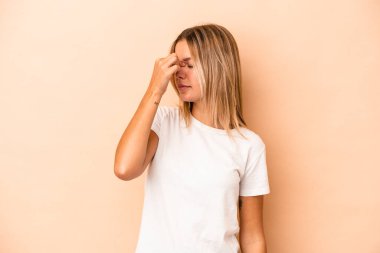 Kafkasyalı genç bir kadın bej arka planda izole edilmiş, başı ağrıyor, yüzüne dokunuyor..
