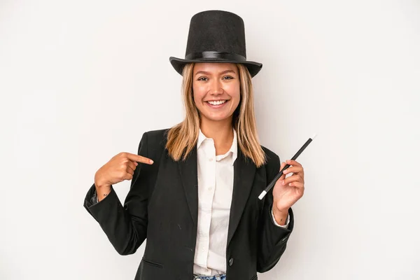 Young caucasian wizard woman holding wand isolated on white background person pointing by hand to a shirt copy space, proud and confident