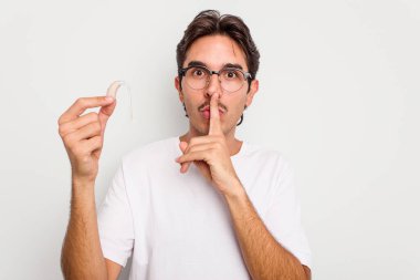 Beyaz arka planda işitme cihazı tutan genç İspanyol bir adam bir sır saklıyor ya da sessizlik istiyor..