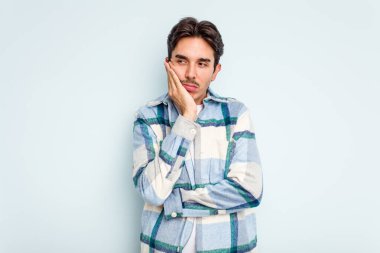 Mavi arka planda izole edilmiş genç bir İspanyol. Sıkılmış, yorgun ve dinlenmeye ihtiyacı var..