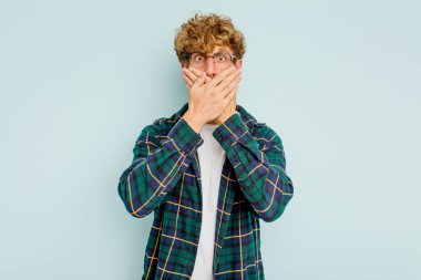 Kafkasyalı genç adam mavi arka planda izole edilmiş ağzı kapalı ve elleri endişeli görünüyor..