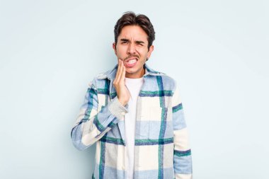 Genç İspanyol bir adam mavi arka planda izole edilmiş güçlü bir diş ağrısı, azıdişi ağrısı var..