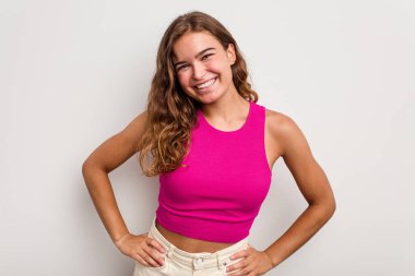 Kafkasyalı genç bir kadın mavi arka planda izole edilmiş. Kendine güvenen, ellerini kalçasında tutan..