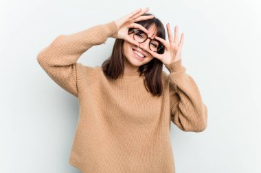 Beyaz arka planda izole edilmiş beyaz tenli genç bir kadın gözlerinde sorun olmadığını gösteriyor.