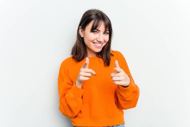 Beyaz arka planda izole edilmiş genç beyaz kadın parmaklarıyla ön tarafı işaret ediyor..