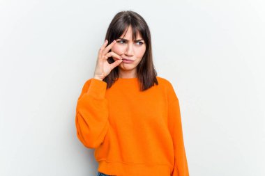 Beyaz arka planda izole edilmiş beyaz tenli genç bir kadın parmakları dudaklarında bir sır saklıyor..