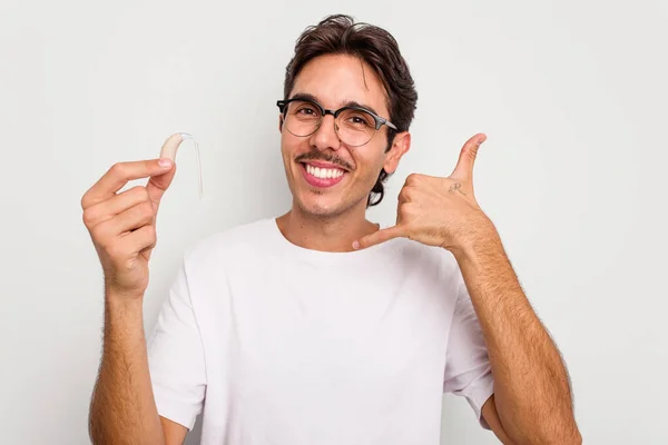 Beyaz Arka Planda Işitme Cihazı Tutan Genç Spanyol Adam Parmaklarıyla — Stok fotoğraf