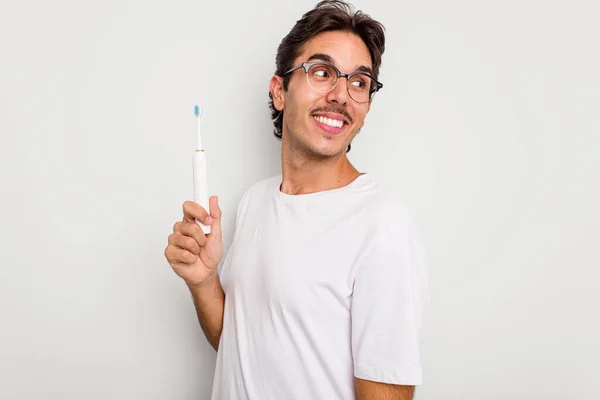 Jonge Spaanse Man Met Elektrische Tandenborstel Geïsoleerd Witte Achtergrond Kijkt — Stockfoto