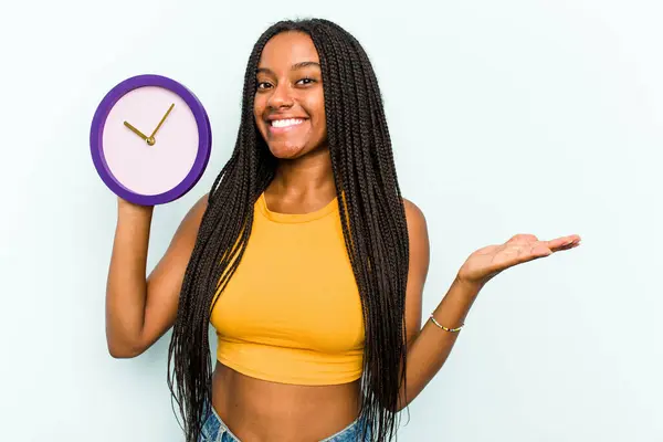 Mavi Arka Planda Bir Saat Tutan Genç Afrikalı Amerikalı Kadın — Stok fotoğraf
