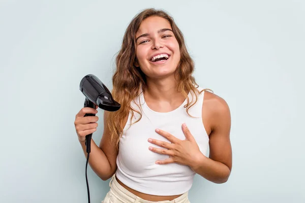 Young Caucasian Woman Holding Hairdryer Isolated Blue Background Laughs Out — Stock Photo, Image