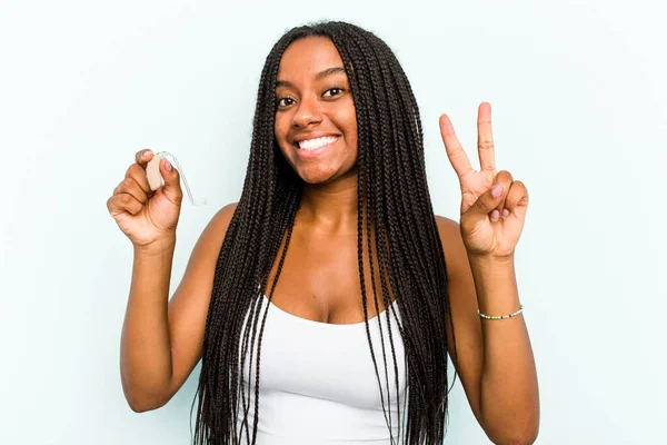 Молодая Афроамериканка Держащая Слуховой Аппарат Синем Фоне Показывает Номер Два — стоковое фото