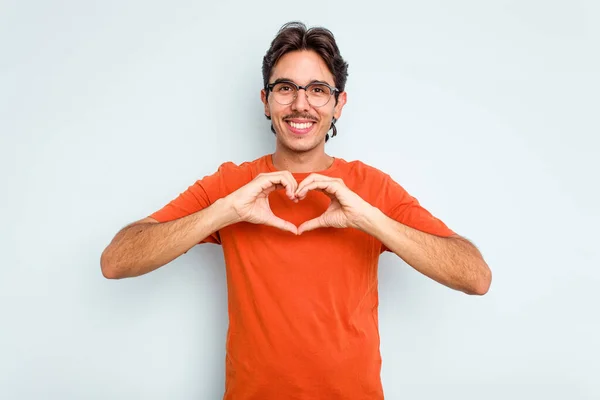 Jonge Spaanse Man Geïsoleerd Blauwe Achtergrond Glimlachend Toont Een Hartvorm — Stockfoto