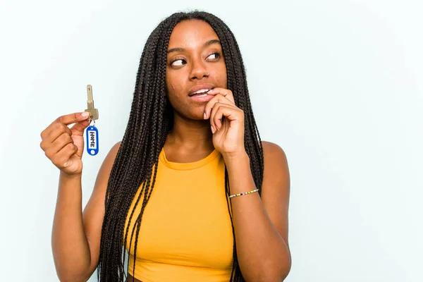 Młoda Afroamerykanka Trzymająca Klucze Domu Niebieskim Tle Zrelaksowana Myśląc Czymś — Zdjęcie stockowe
