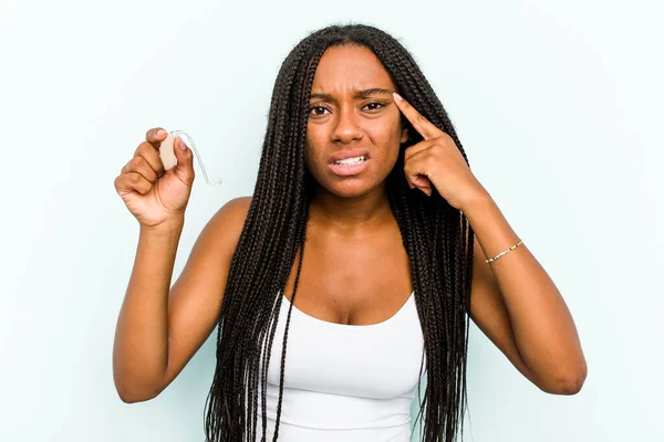 年轻的非裔美国妇女 手持蓝色背景的助听器 用食指表示失望的姿态 — 图库照片