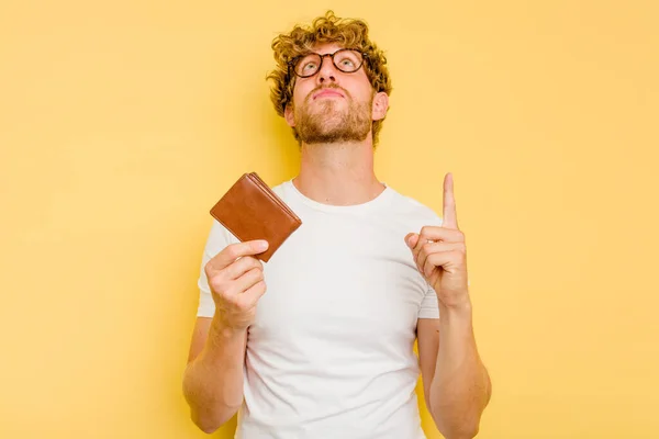 Jovem Caucasiano Segurando Uma Carteira Isolada Fundo Amarelo Apontando Cabeça — Fotografia de Stock