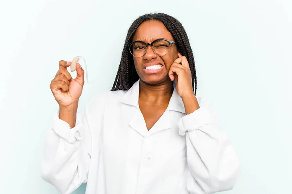 Young African American Otorhinolaryngologist Woman Holding Hearing Aid Isolated Blue — Stock Photo, Image