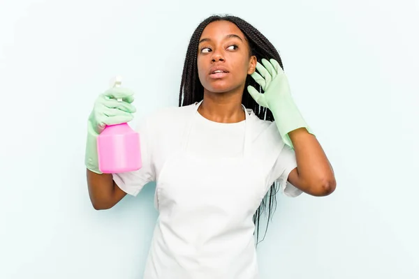 Młoda Afroamerykanka Sprzątaczka Odizolowana Niebieskim Tle Próbująca Słuchać Plotek — Zdjęcie stockowe