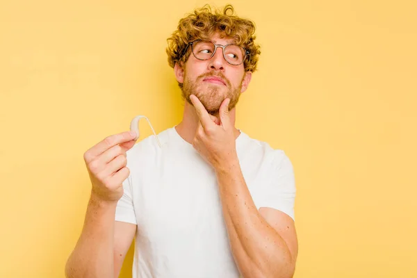 Junger Kaukasischer Mann Mit Hörgerät Isoliert Auf Gelbem Hintergrund Schaut — Stockfoto