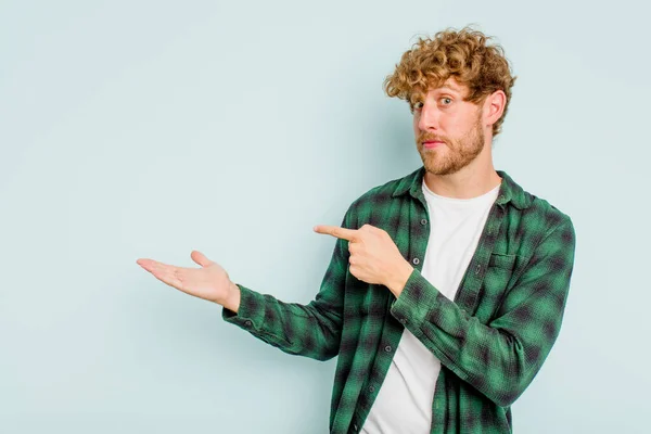 Junge Kaukasische Mann Isoliert Auf Blauem Hintergrund Aufgeregt Hält Eine — Stockfoto