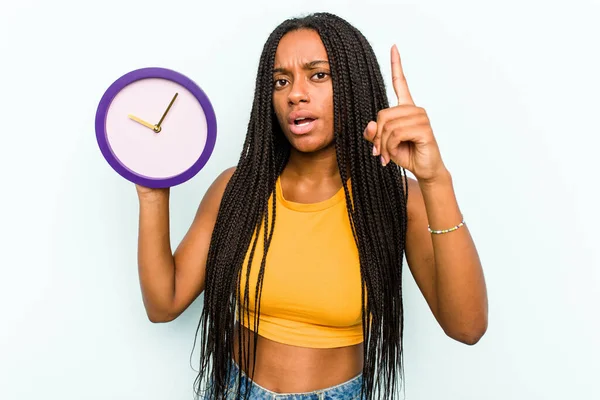 Ung Afroamerikansk Kvinna Håller Klocka Isolerad Blå Bakgrund Har Idé — Stockfoto