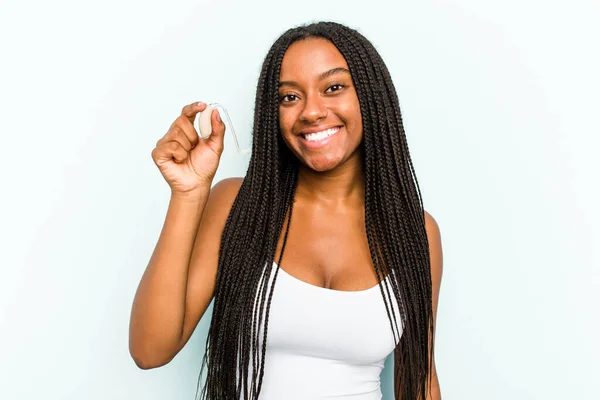 Молодая Афроамериканка Держит Слуховой Аппарат Голубом Фоне Счастливой Улыбающейся Веселой — стоковое фото