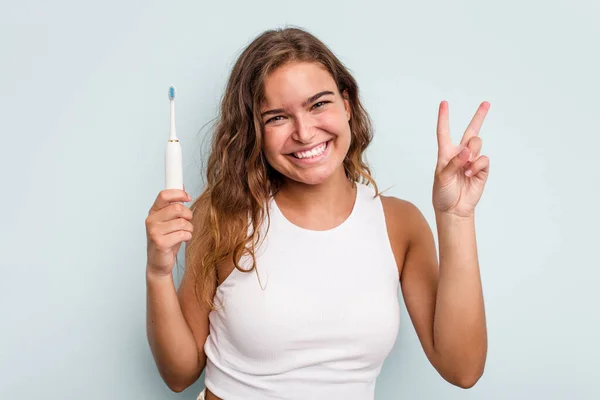 Молодая Белая Женщина Электрической Зубной Щеткой Голубом Фоне Показывает Номер — стоковое фото