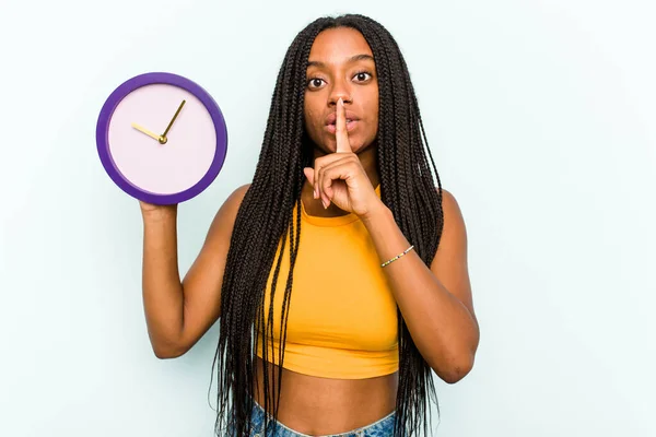 Ung Afroamerikansk Kvinna Håller Klocka Isolerad Blå Bakgrund Hålla Hemlighet — Stockfoto