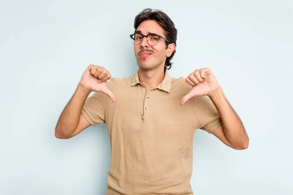 Young Hispanic Man Isolated Blue Background Showing Thumb Disappointment Concept — стоковое фото