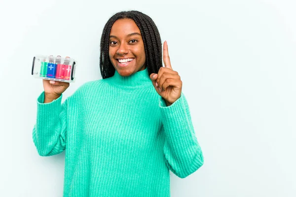 年轻的非洲裔美国女人把电池盒隔离在蓝色背景下 显示出第一手指 — 图库照片