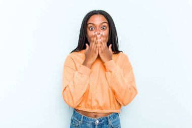 Mavi arka planda saç örgüsü olan genç Afrikalı Amerikalı kadın elleriyle ağzını kapatırken şok oldu..
