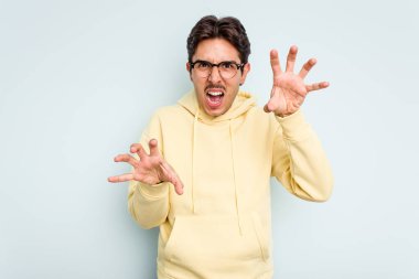 Mavi arka planda izole edilmiş genç İspanyol adam gergin elleriyle çığlık atıyor..