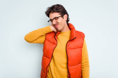 Genç İspanyol bir adam mavi arka planda izole edilmiş. Stres yüzünden boynu ağrıyor. Masaj yapıyor ve elle dokunuyor..