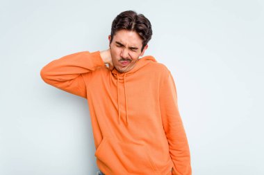 Genç İspanyol bir adam mavi arka planda izole edilmiş, sabit yaşam tarzından dolayı boyun ağrısı çekiyor..