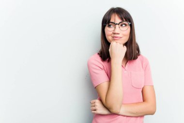Beyaz arka planda izole edilmiş genç beyaz kadın rahatlamış bir şeyin fotokopi odasına baktığını düşünüyor..
